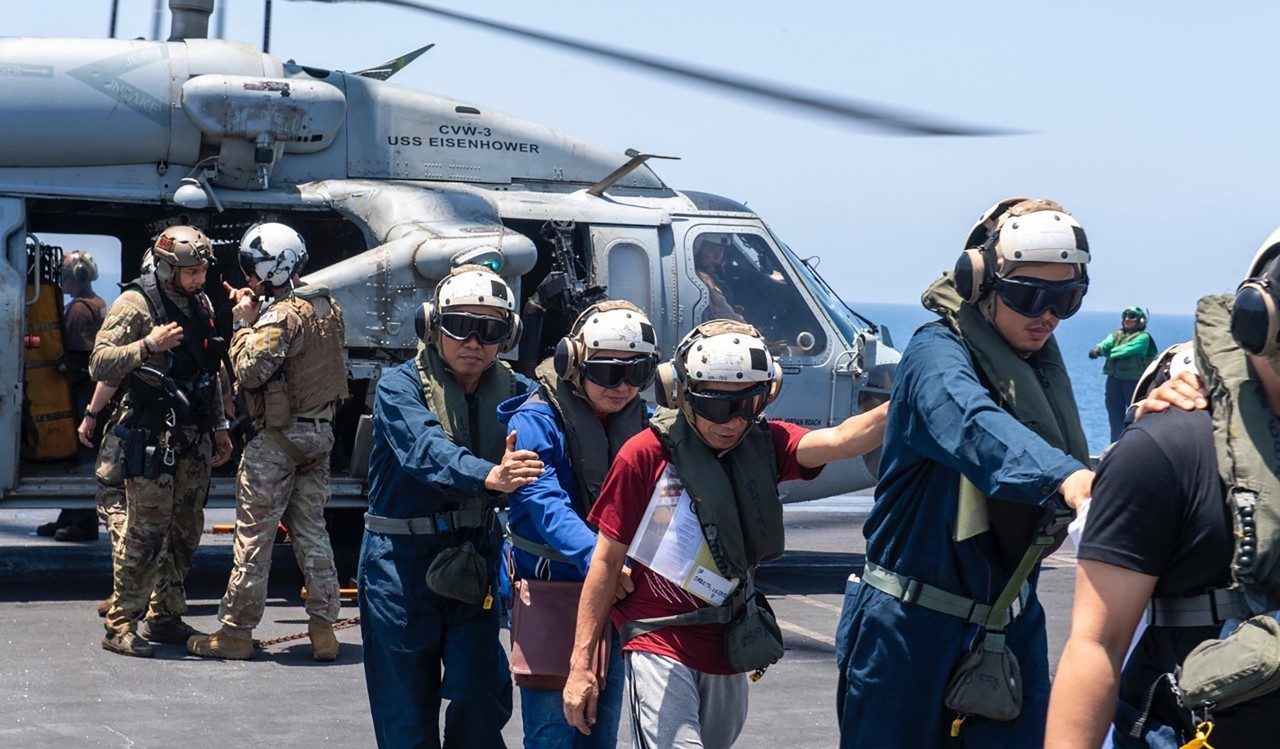 Civilian mariners deplane aboard a US Navy aircraft carrier following an at sea rescue by HSM-74 aircrews in the Red Sea.